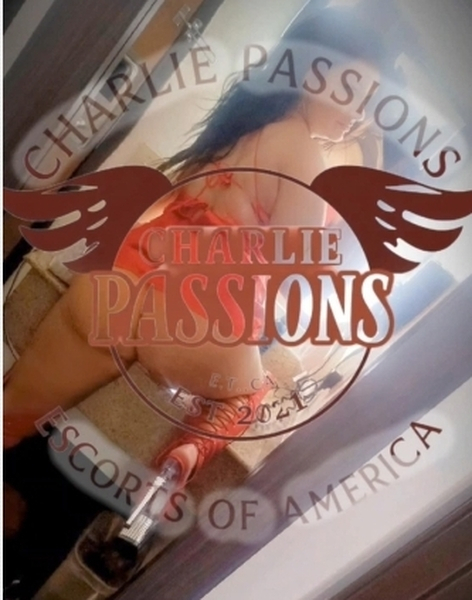 Charlie Passions smiling seductively in a red dress, highlighting her allure